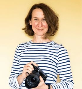 Portrait of Sara holding a camera for the info page.